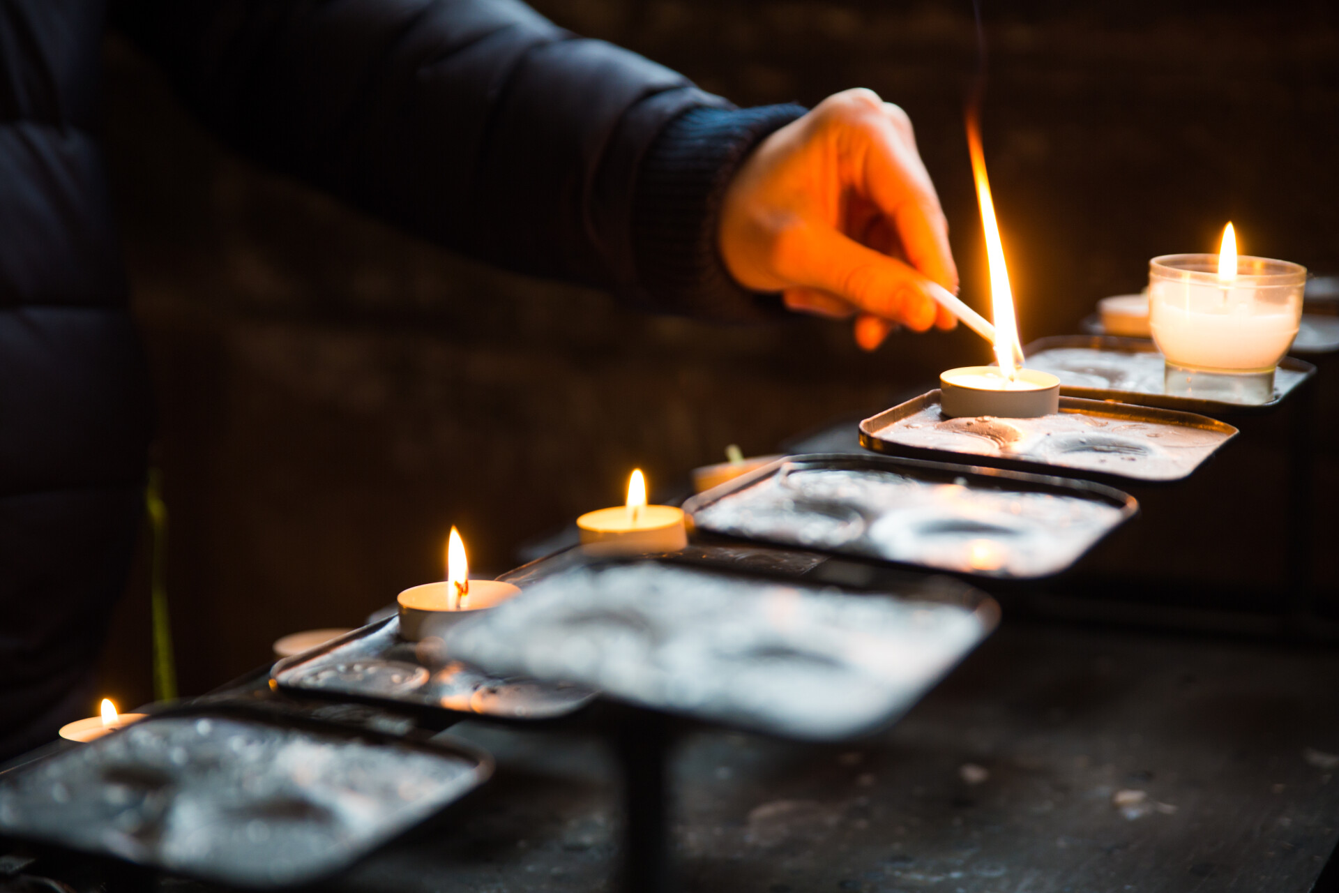 Hands tuning on candles in a church 2025 01 08 03 02 23 utc